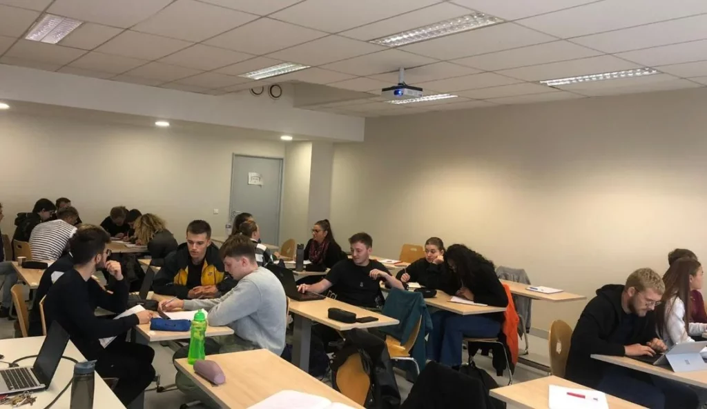 Étudiants IPMS en travaux de groupe dans une salle de cours moderne et lumineuse.