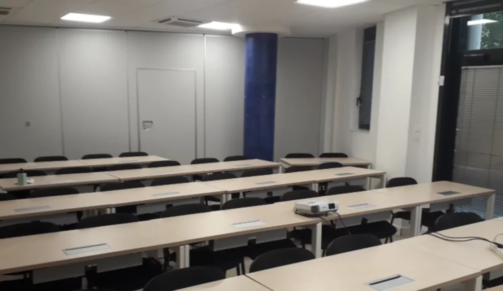 Salle de cours équipée du campus IPMS Lyon, avec bureaux alignés et vidéoprojecteur.