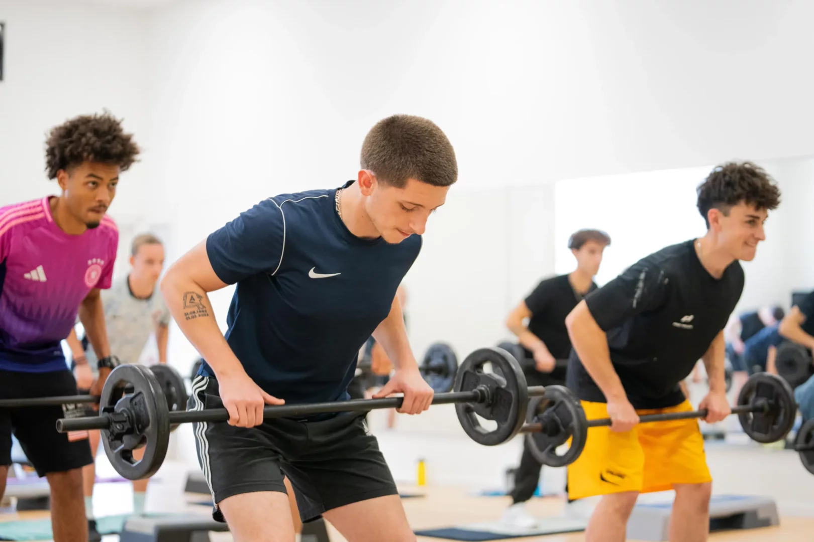 Groupe de stagiaires réalisant un exercice de rowing barre en cours collectif de musculation