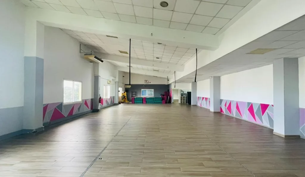 Grande salle de cours collectifs IPMS Saint-Louis avec sol parquet et décor géométrique rose et gris.