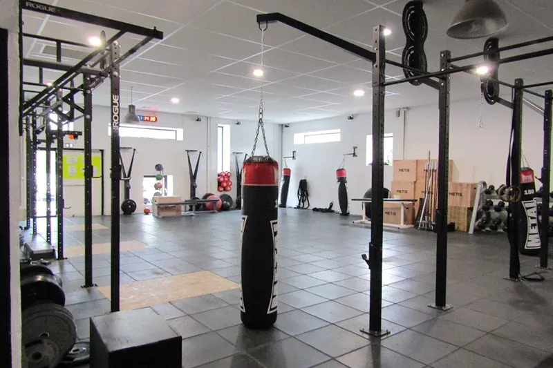 Salle de cross training IPMS Pau équipée de racks, sacs de frappe et matériel fonctionnel.