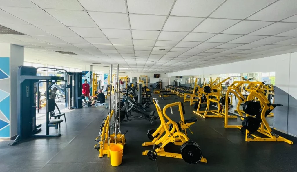 Salle de musculation IPMS Saint-Louis équipée de machines jaunes et miroirs panoramiques.