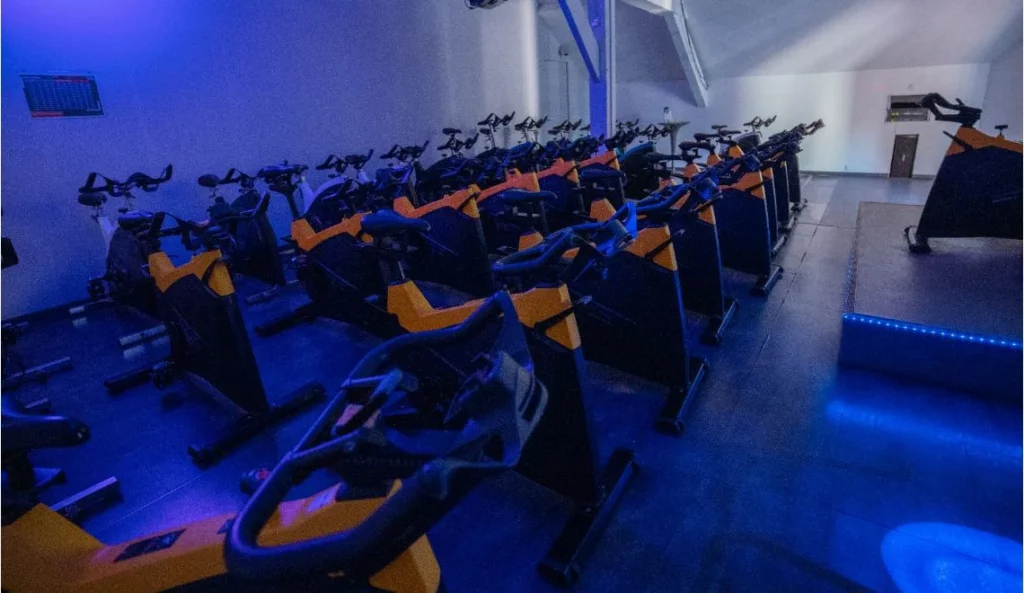 Salle de biking à l’IPMS : rangée de vélos d’intérieur sous lumière bleue.