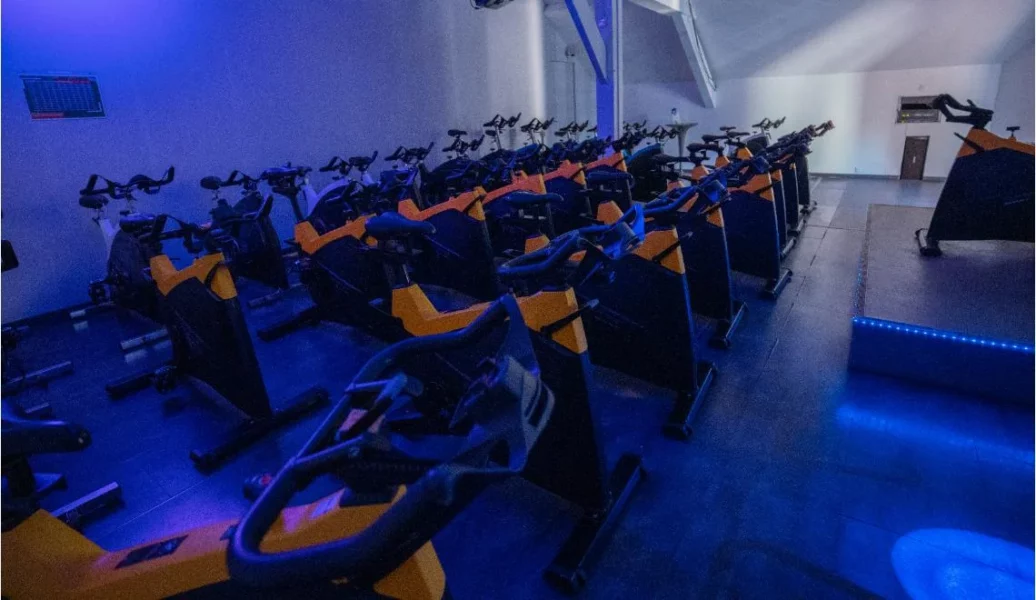 Salle de biking à l’IPMS : rangée de vélos d’intérieur sous lumière bleue.
