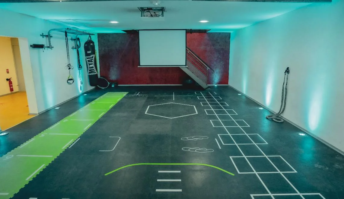 Salle d’entraînement fonctionnel IPMS avec marquages au sol et mur rouge.