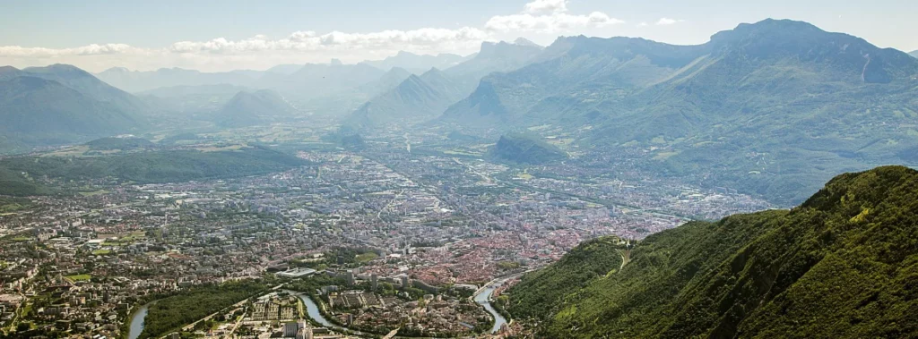 Vue aérienne de Grenoble entourée des montagnes, cadre du campus IPMS.