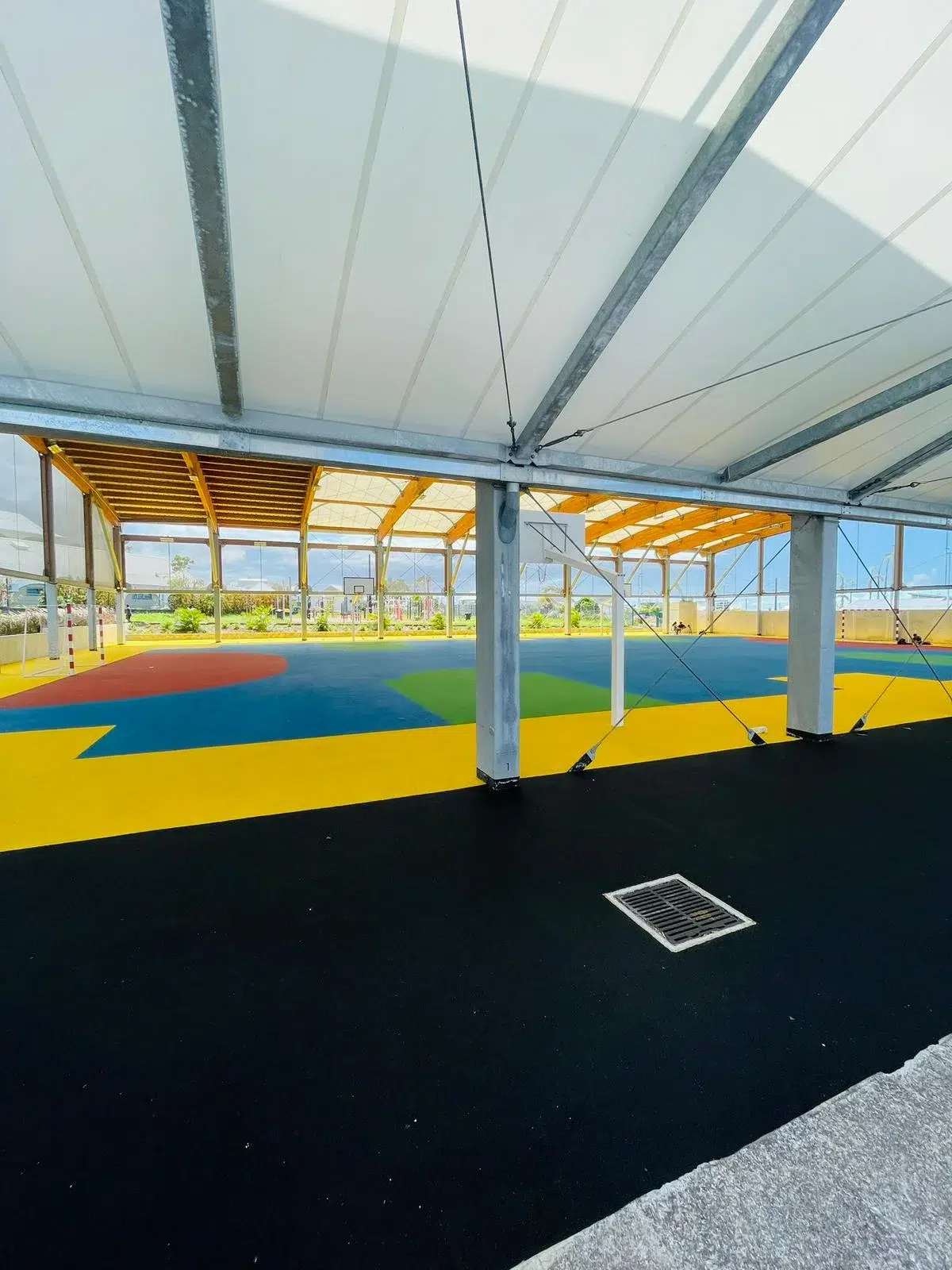 Vue latérale de la halle couverte IPMS Saint-André, sol coloré et structure bois.