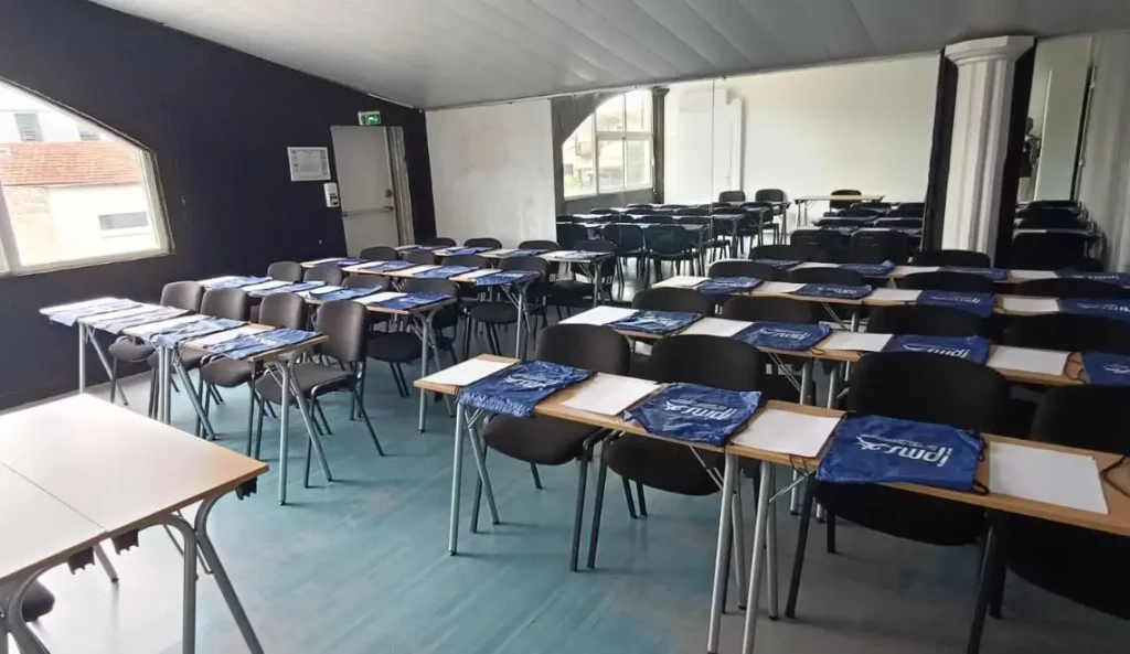 Salle de cours IPMS Bordeaux préparée pour la rentrée des étudiants BPJEPS, tables et sacs IPMS disposés.