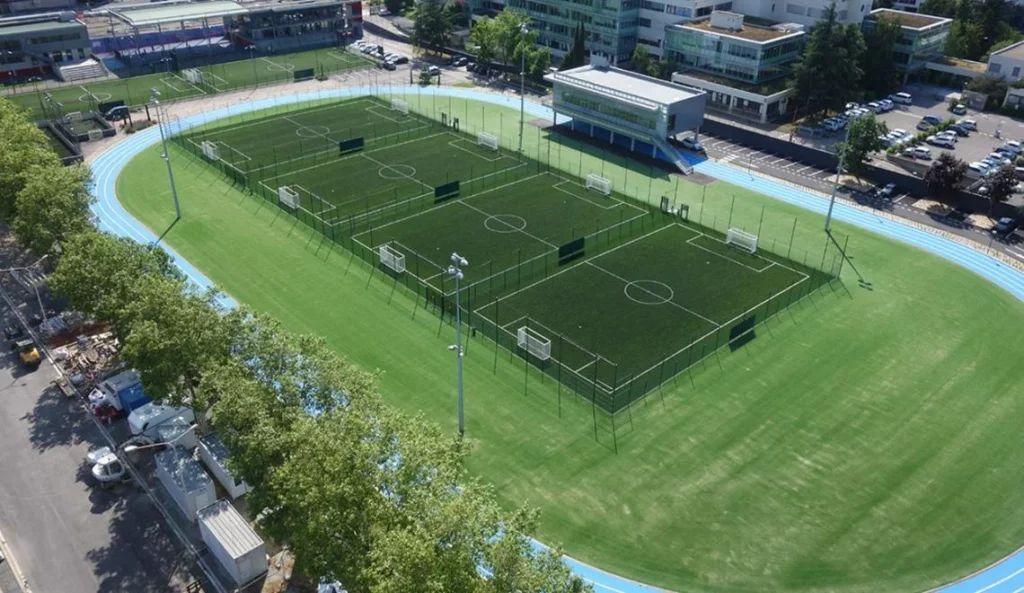 Terrain extérieur de sport collectif à Lyon, entouré d’une piste bleue d’athlétisme.