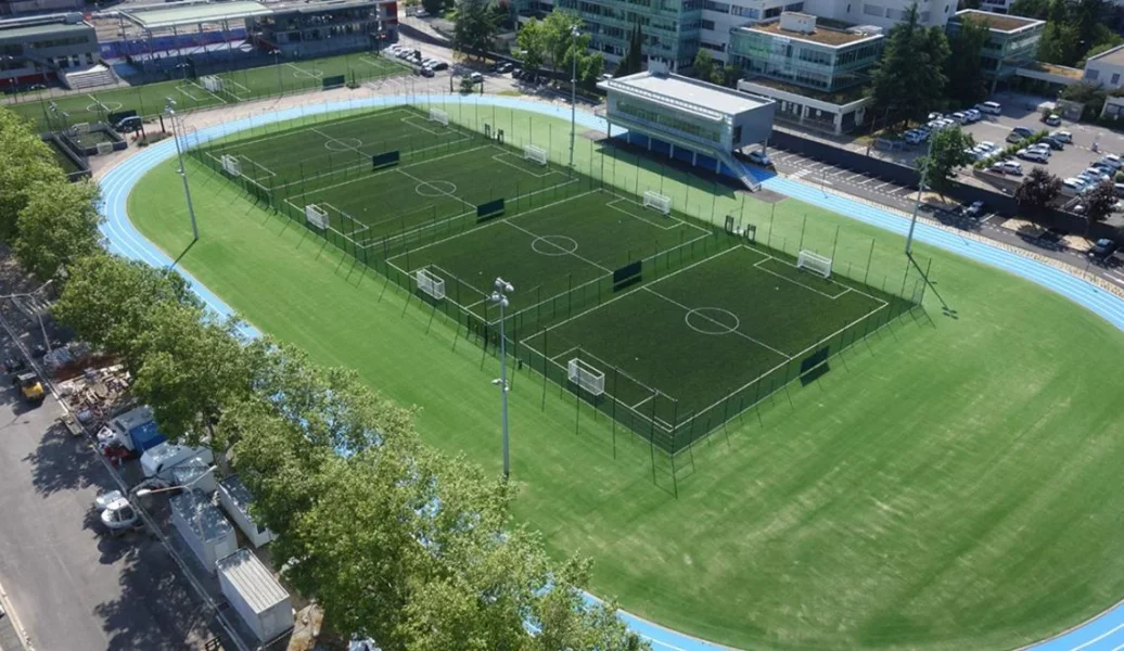 Terrain extérieur de sport collectif à Lyon, entouré d’une piste bleue d’athlétisme.