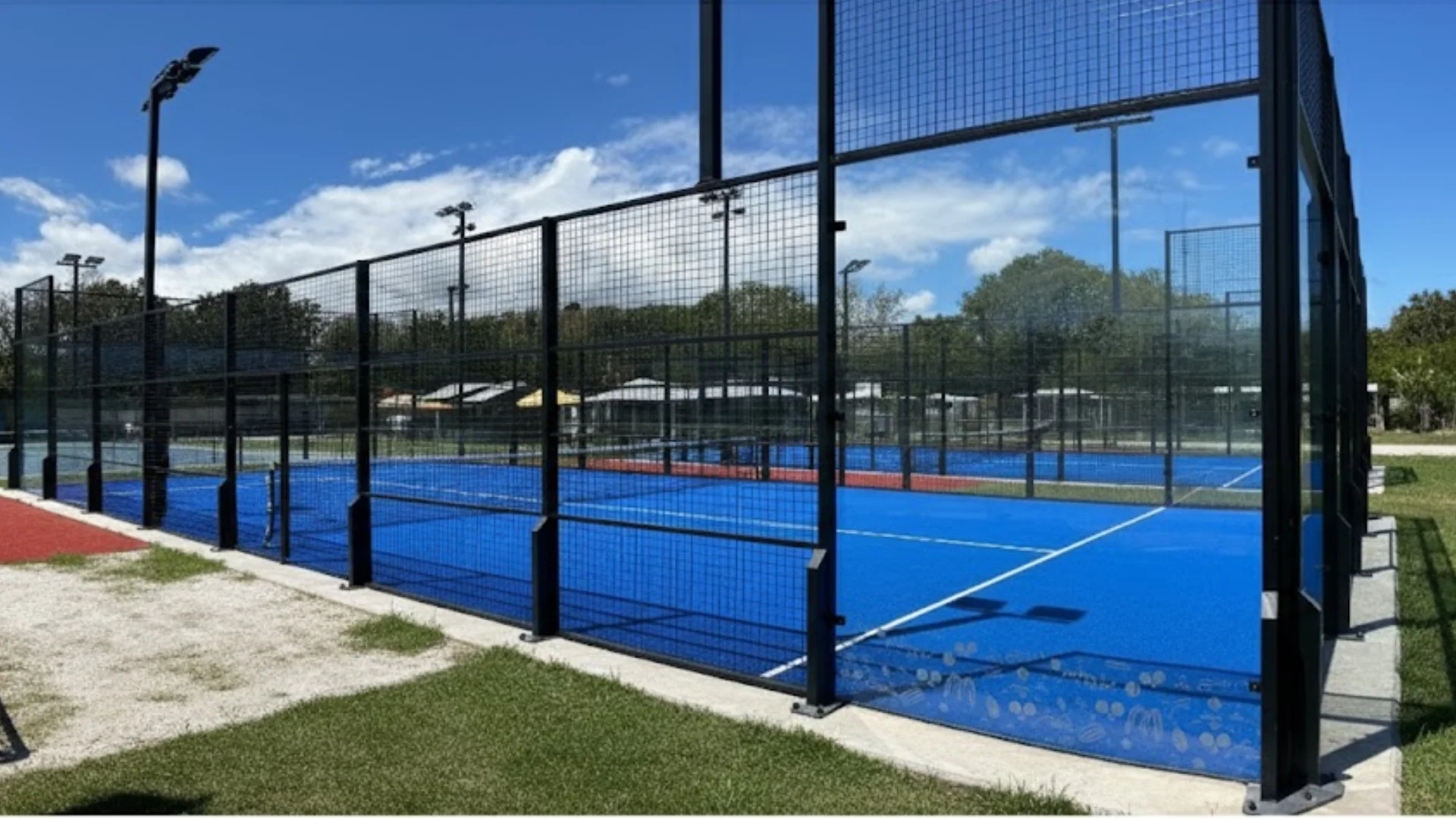 Terrain de padel bleu du campus IPMS Saint-Denis, entouré de grillages et palmiers.