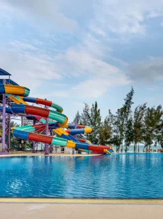 Complexe aquatique avec toboggans colorés et grand bassin extérieur, illustrant les environnements de travail des futurs maîtres-nageurs.