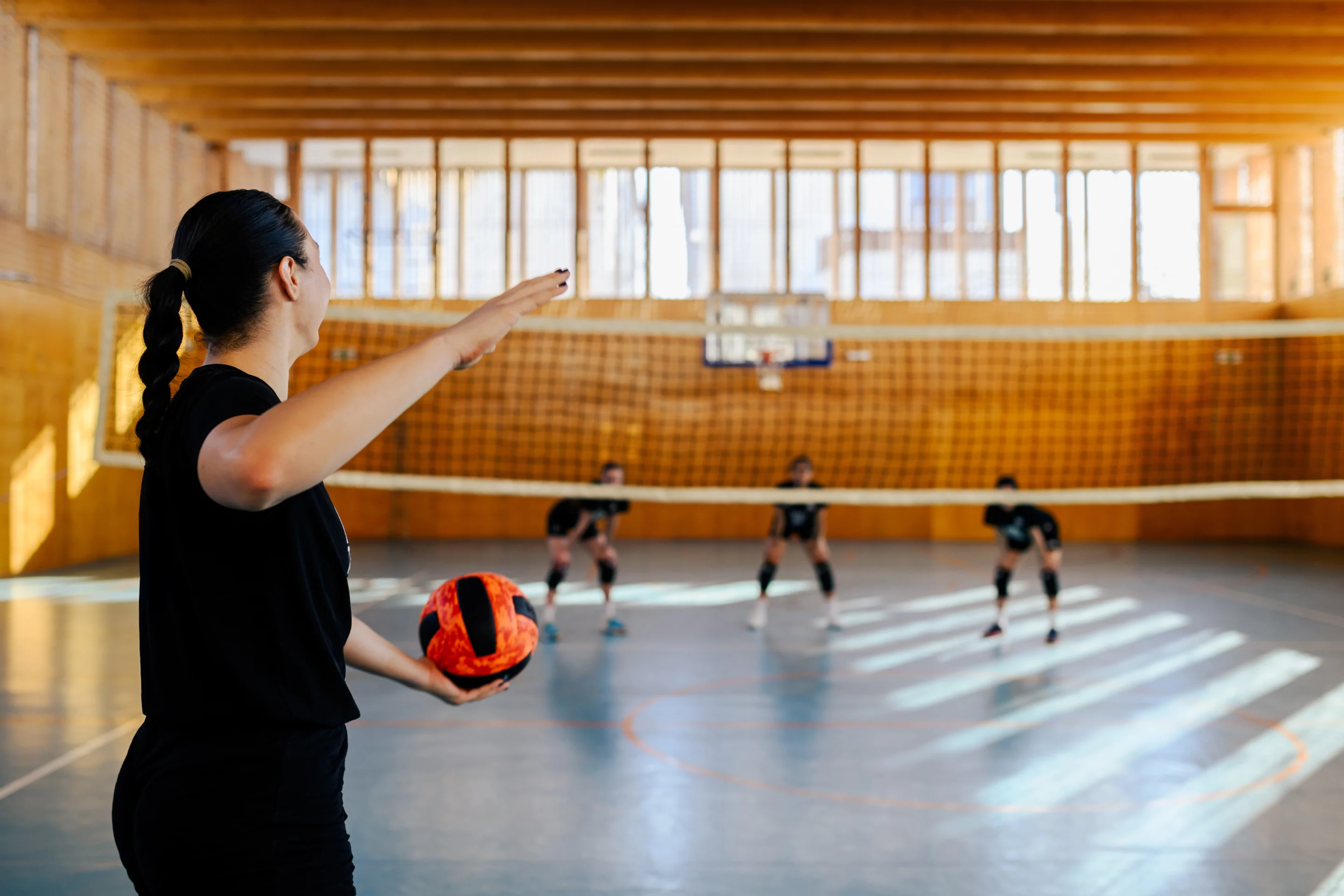 Coach sportive encadrant un groupe au volley-ball dans un gymnase, représentant la pratique en milieu sportif.