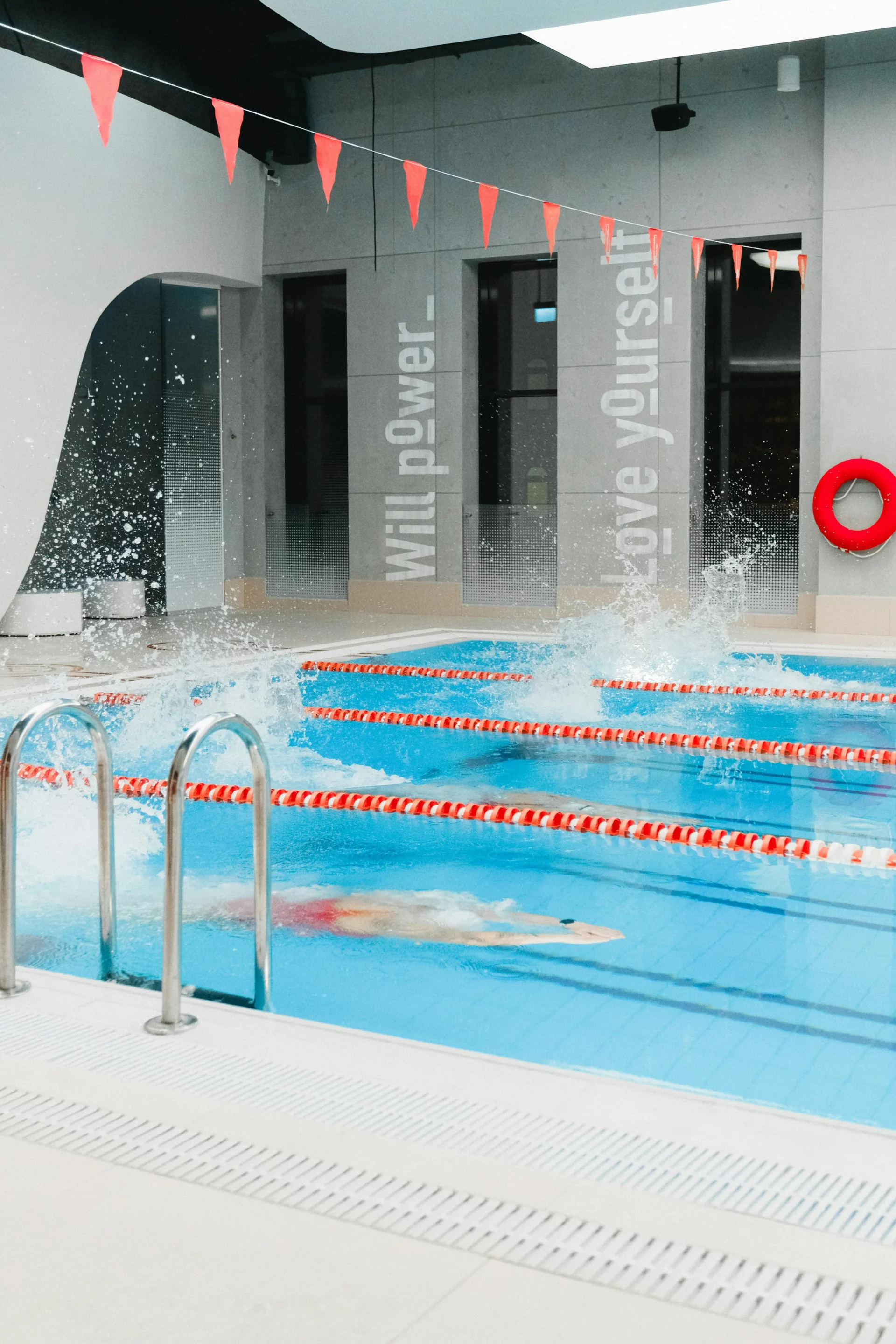 Nageurs en entraînement intensif dans une piscine intérieure moderne avec décorations motivationnelles.