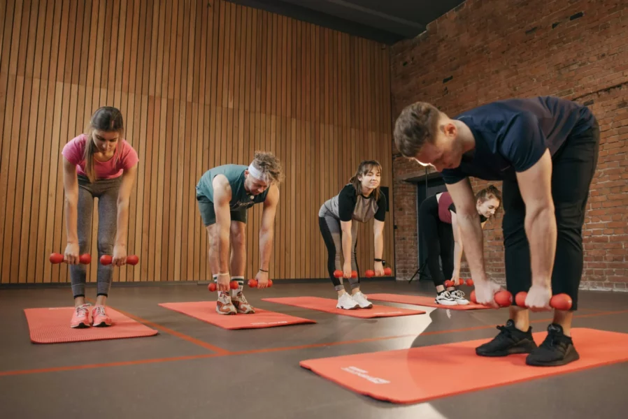 Groupe de participants réalisant un travail musculaire avec haltères légers lors d’une séance encadrée en intérieur.