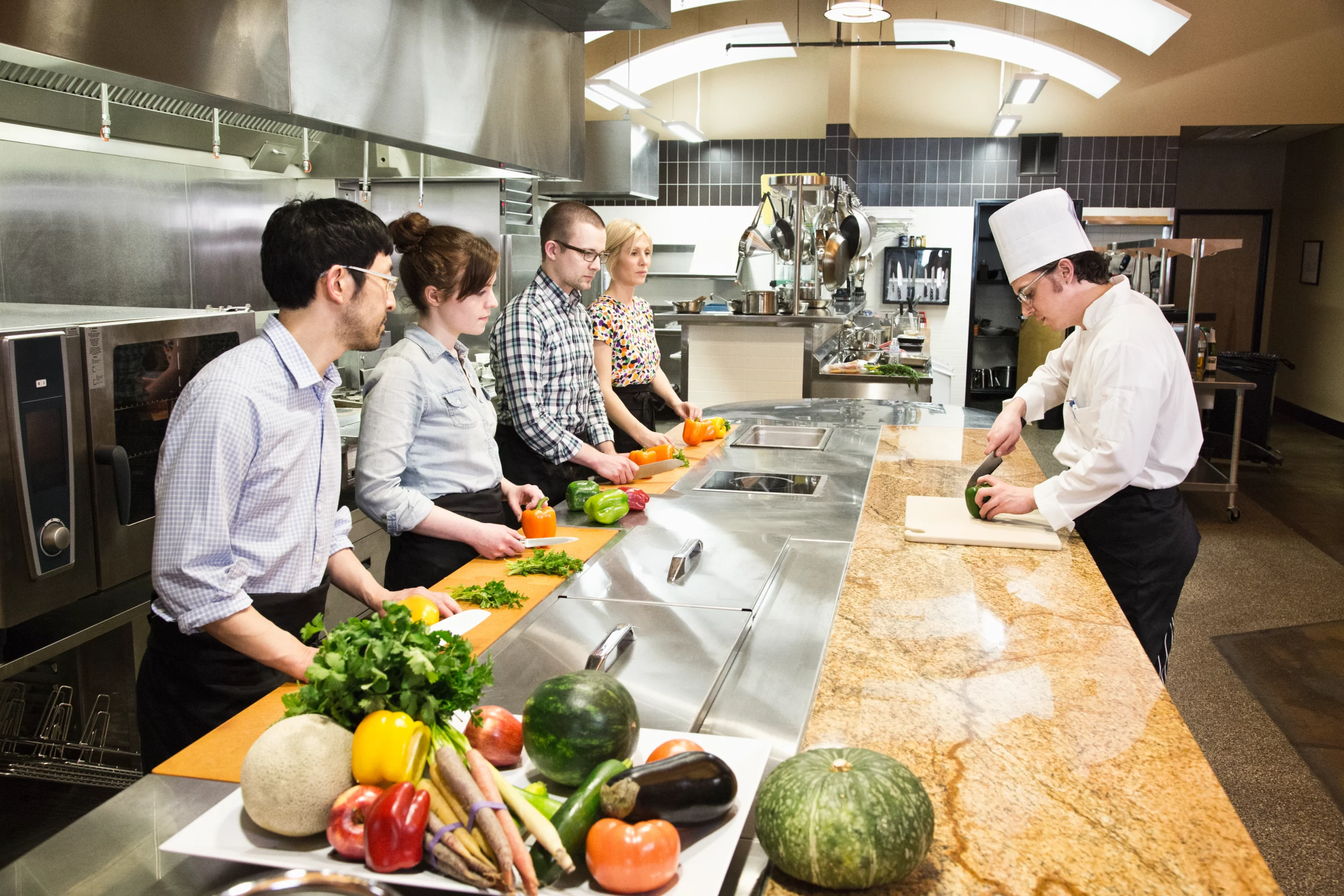 Groupe d’apprenants observant un chef lors d’un atelier cuisine en restauration collective ou cuisine centrale.