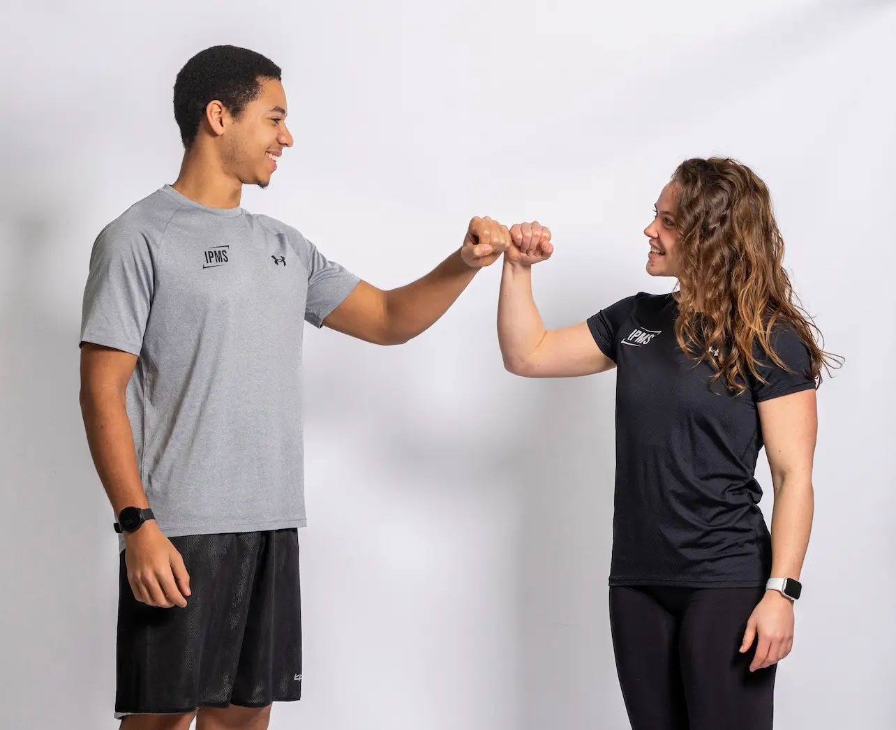 Deux stagiaires IPMS souriants se congratulant avec un check du poing en tenue sportive