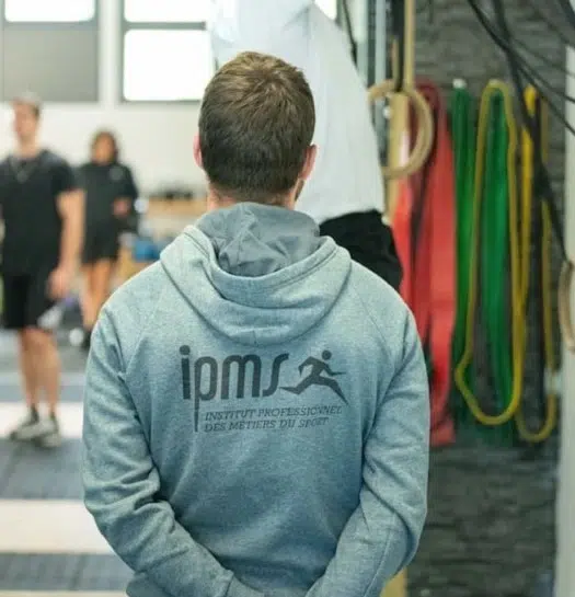 Stagiaire IPMS en sweat à capuche observant une séance de coaching en salle de cross-training