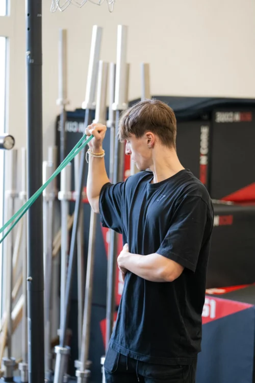 Stagiaire BPJEPS AF réalisant un exercice avec bande élastique de résistance en salle de musculation